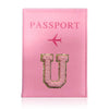 A pink leather passport holder with the word PASSPORT and a gold initial U embossed on it.