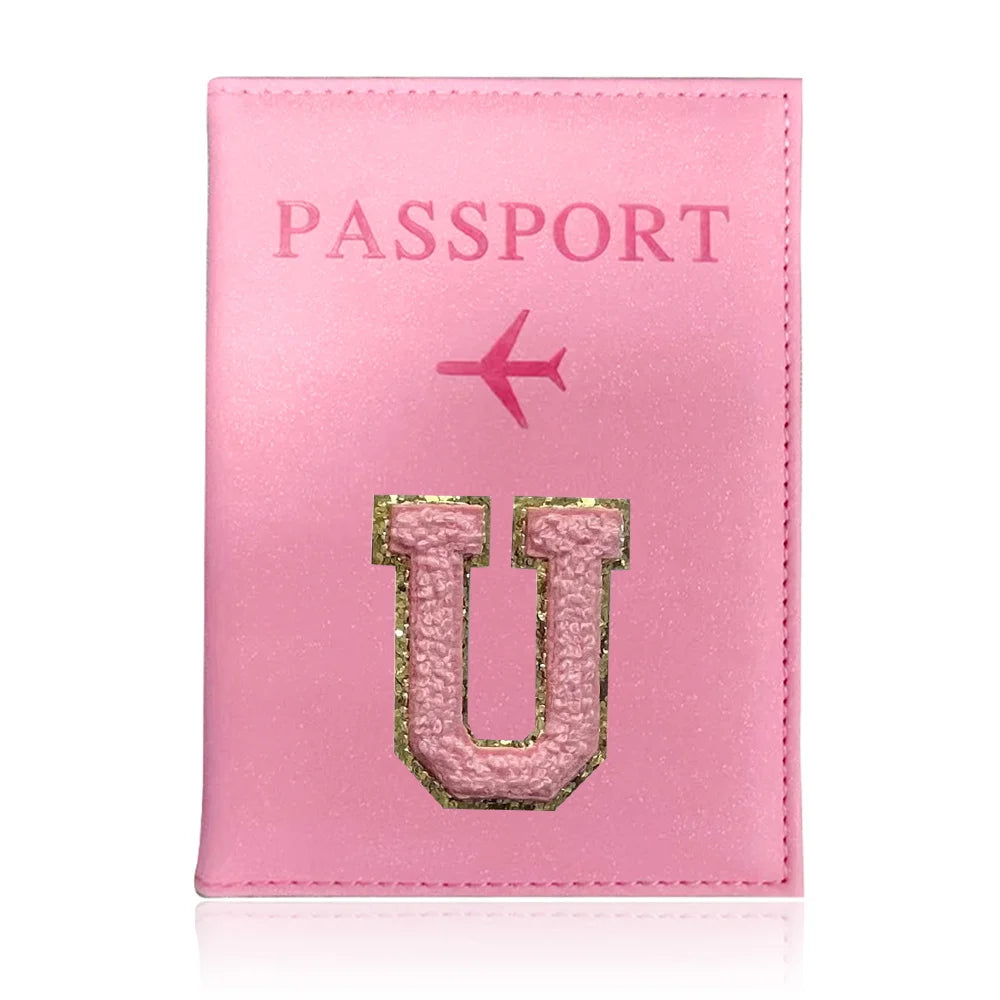 A pink leather passport holder with the word PASSPORT and a gold initial U embossed on it.