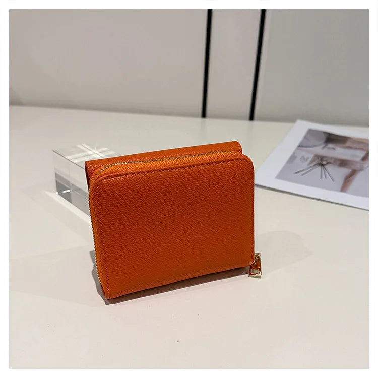 An orange card holder with a zipper closure is displayed on a white surface.