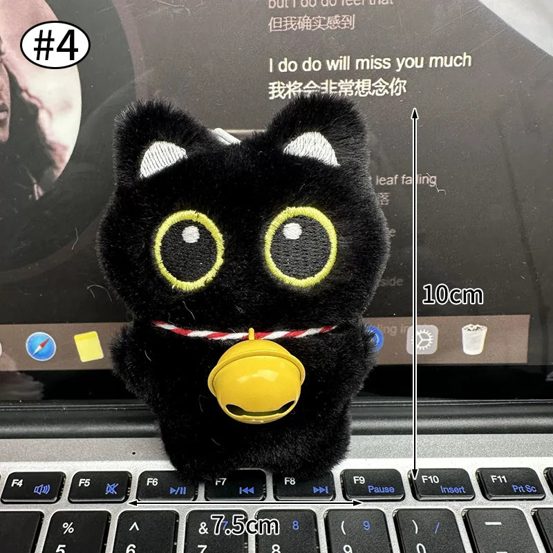 Colgante de peluche de gato negro sobre el teclado de una laptop.