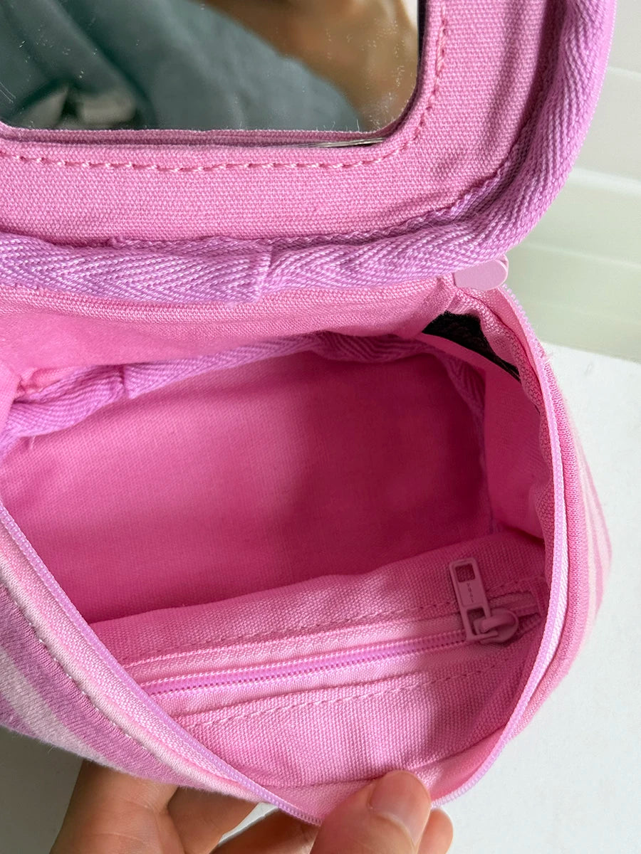 A pink striped Y2K makeup bag with a zipper is shown open, revealing a pink cotton toiletry pouch inside.