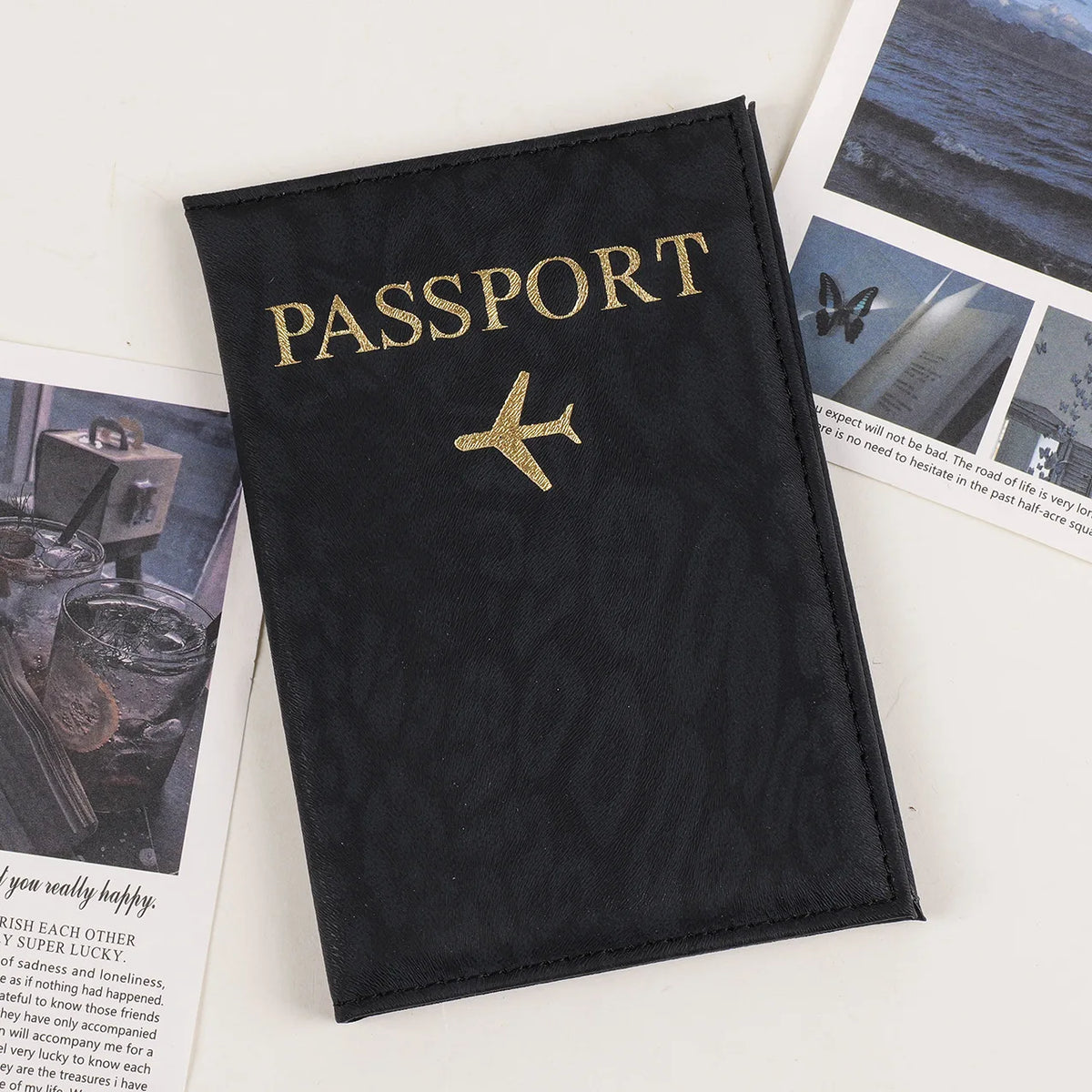 Black passport holder with gold foil lettering and a gold airplane emblem on a white background.