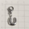 A silver stainless steel alphabet letter charm shaped like the letter U, displayed on a ruler.