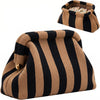 A striped knit clutch bag in tan and black stripes, shown with a small tray of cards.