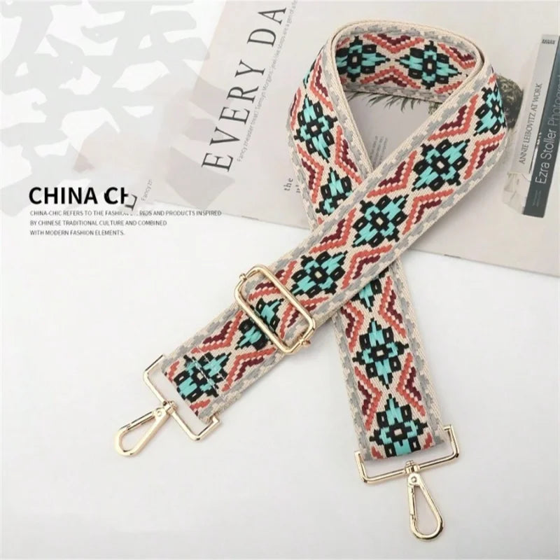 A patterned fabric strap featuring geometric designs in teal, pink, and beige, shown against a light background.