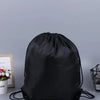 Black gym drawstring backpack with multiple pockets lying on a gray surface.