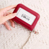 A hand holds a red accordion wallet with an RFID protected credit card inside, attached to a silver chain.