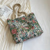 A floral patterned bohemian corduroy tote bag resting on a white surface next to a piece of light-colored fabric.