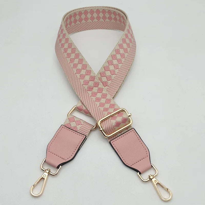 A pink and white checkered braided nylon bag strap with metal hooks.