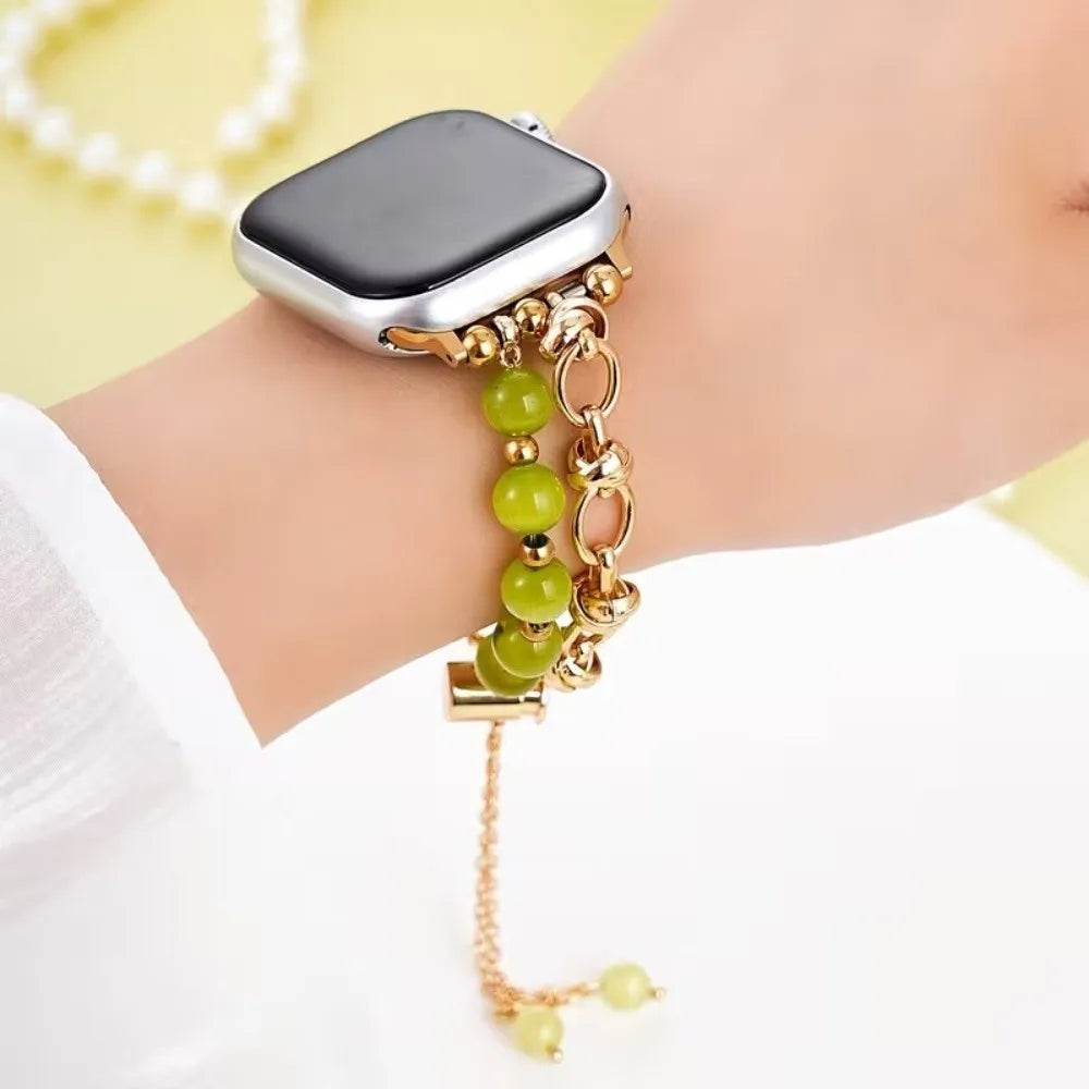 Silberne Smartwatch mit goldfarbenem Metallarmband und kleinen grünen Kristallperlen