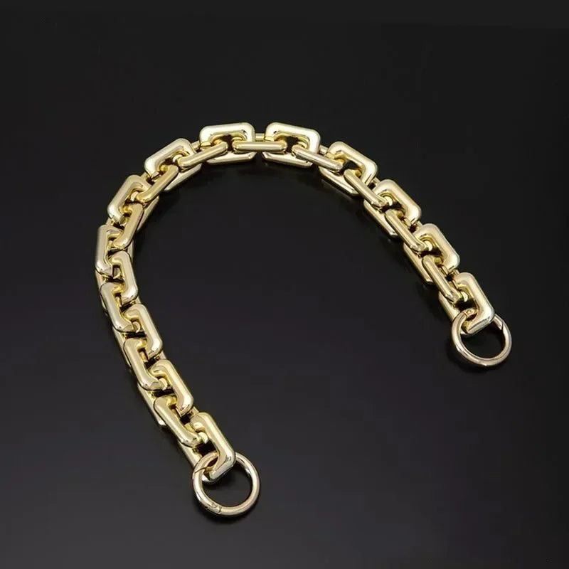 A gold-colored adjustable acrylic purse chain strap for a shoulder bag, displayed against a dark background.
