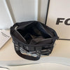 A black chains and rivet nylon shoulder bag resting on a white surface.