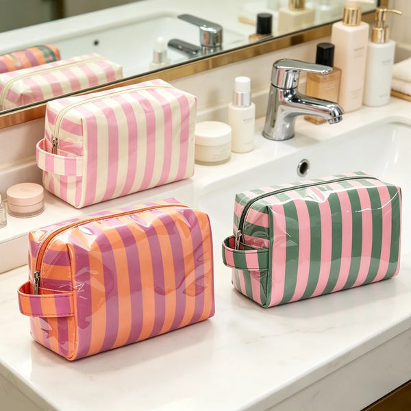 A pink and striped cosmetic storage bag resting on a white marble bathroom counter next to a sink.