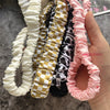 Eine Hand hält mehrere bunte, geraffte Schlüsselketten und Lanyards für Handys und Schlüssel.