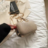 A beige glitter crossbody evening clutch bag resting on a white sheet next to a book.