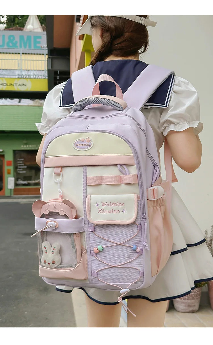 A woman is wearing a light purple and cream Candy Color Campus backpack with white trim and pink accents.