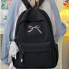 A black backpack with a pink bow embroidery and a white tassel attached to the zipper.