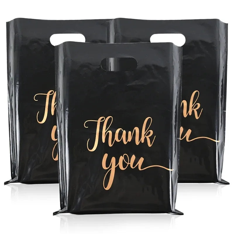 Three black plastic gift bags with gold script text saying Thank you