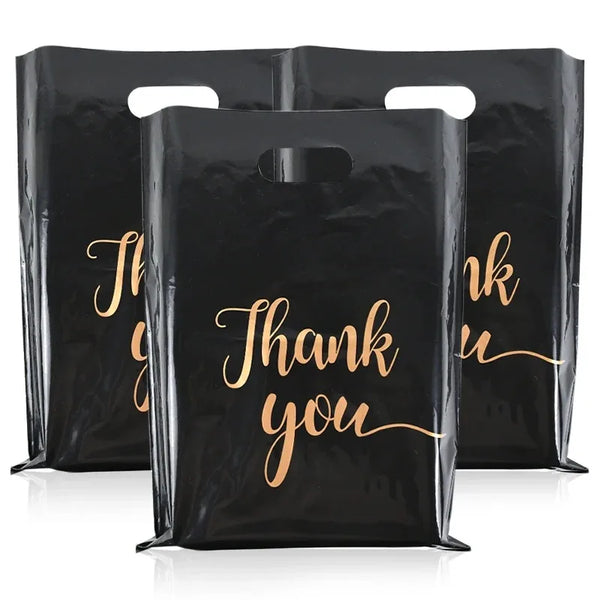 Three black plastic gift bags with gold script text saying Thank you