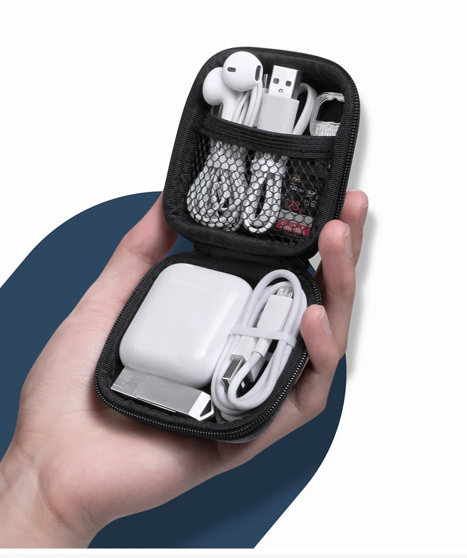 Una mano sostiene un estuche negro abierto para AirPods y accesorios, mostrando auriculares y cables de carga dentro.
