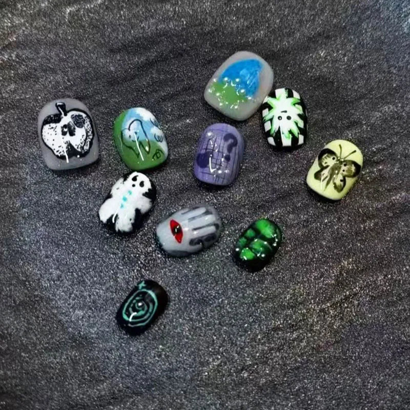 A collection of colorful, cartoon-themed press-on nails shaped like various animals and objects on a dark surface.