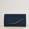 A dark navy velvet evening clutch with a gold-toned fold detail resting on a light surface.