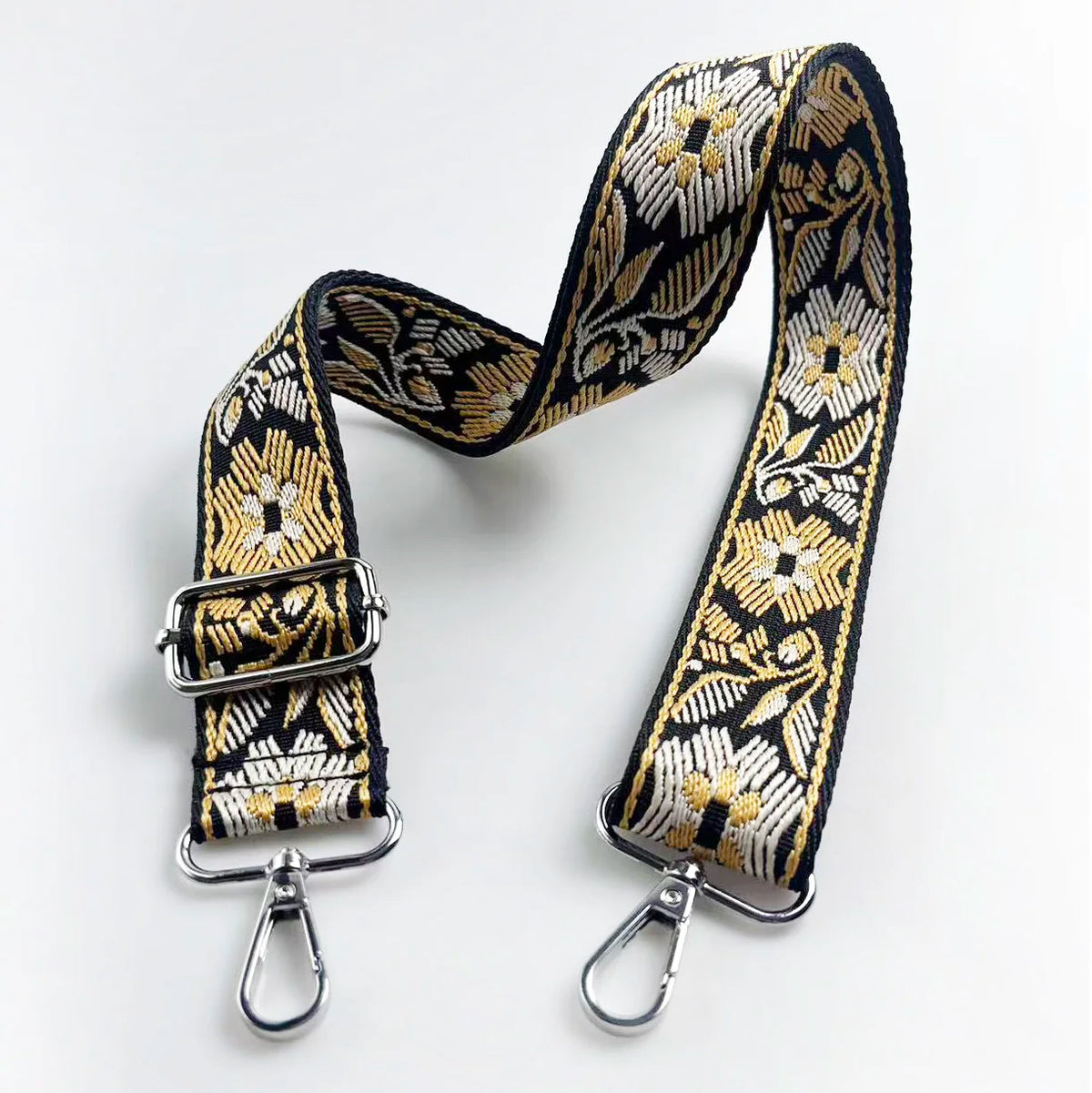 A black and gold patterned jacquard strap for an adjustable crossbody bag.