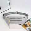 A light gray nylon crossbody fanny pack with a zippered pocket and a smartphone resting on it.