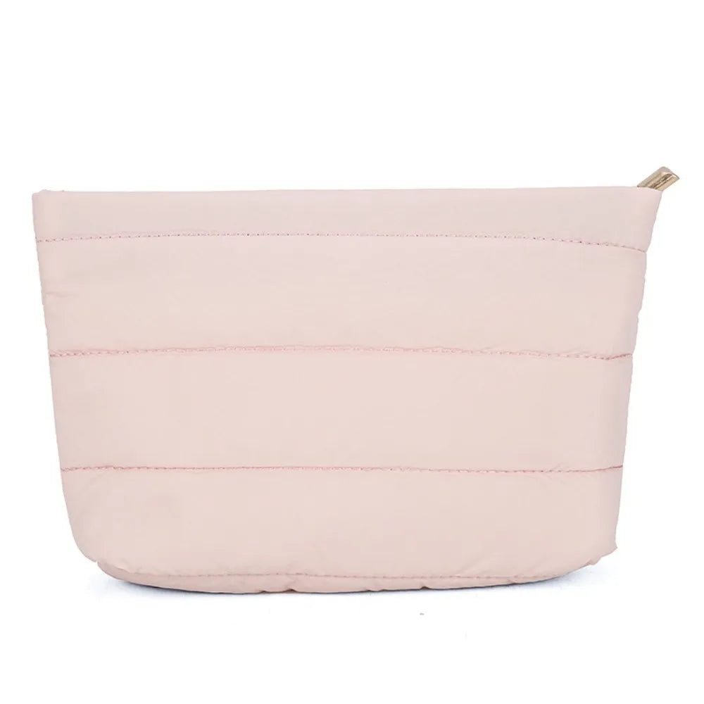 A light pink quilted cosmetic travel bag with a zipper closure.
