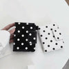 A black and white polka dot passport holder with multi-card slots is shown on a white table.
