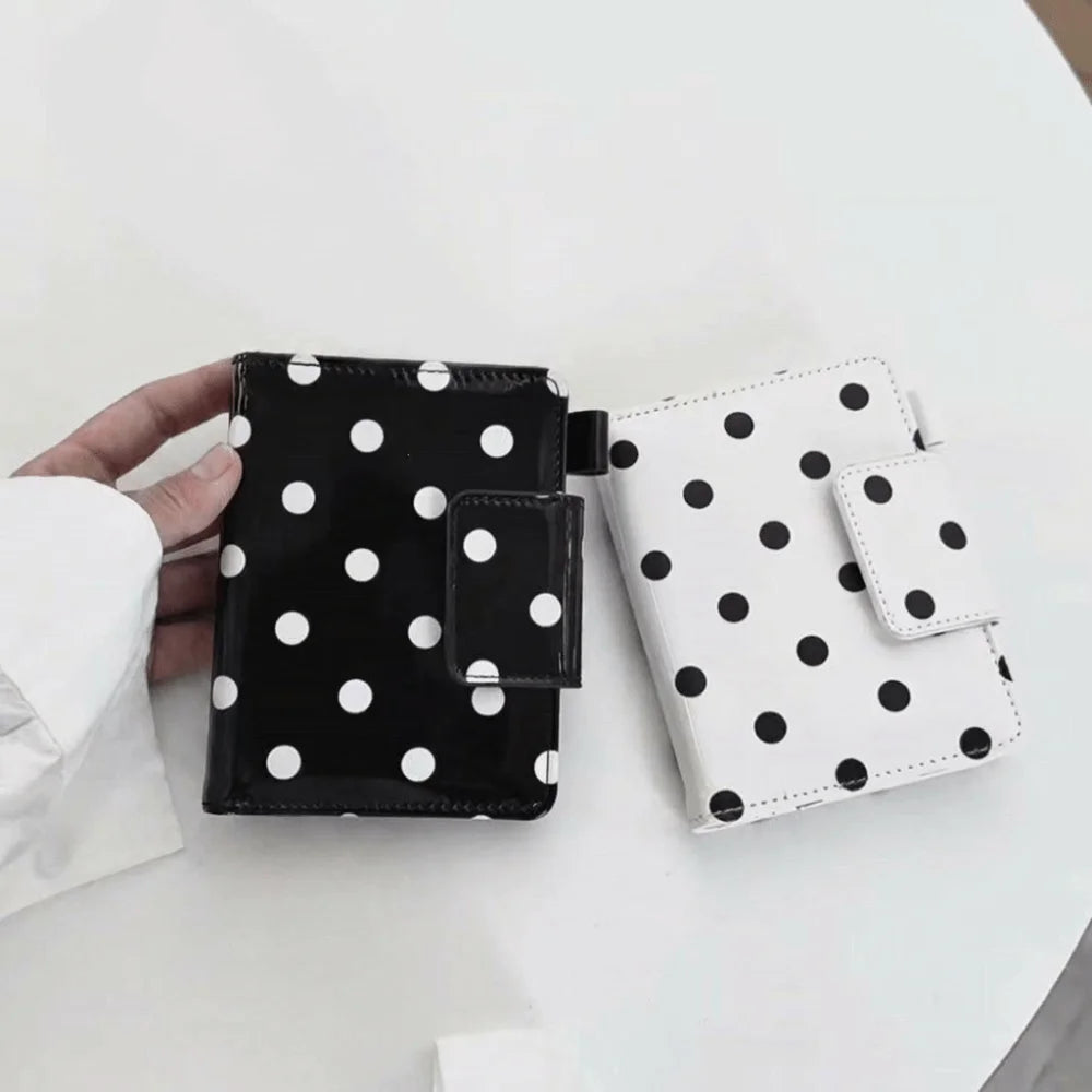 A black and white polka dot passport holder with multi-card slots is shown on a white table.