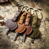 A collection of genuine leather key fob covers and keychain rings laid on aged paper.