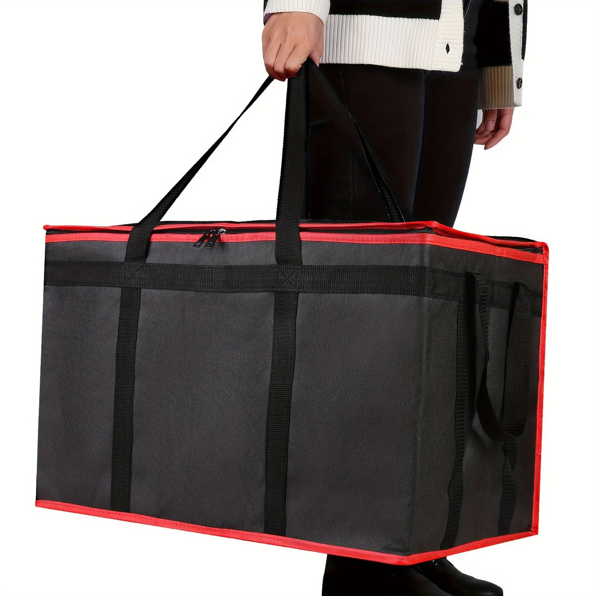 A black reusable insulated food delivery bag with red trim being held by a person.