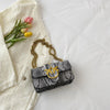 A black and white patterned elegant retro crossbody bag rests on a white linen shirt.