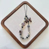 Leopard print bowknot phone lanyard featuring heart and various beads displayed on a wooden tray.