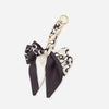 A black and white patterned fabric bow with a gold chain strap extension for a handbag.