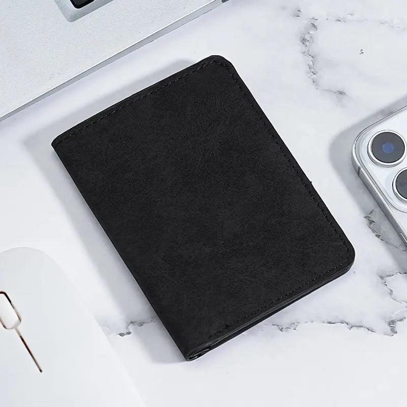 A black ultra-thin multi-slot card wallet resting on a white marble surface next to a smartphone.