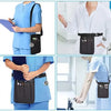 A nurse wearing blue scrubs demonstrates a black organizer belt waist bag with multiple pockets.