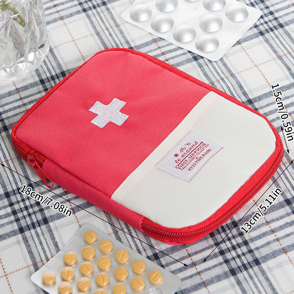 A pink pouch containing a first aid kit with pills and a white cross symbol, placed on a plaid cloth.