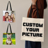 A person holds a beige tote bag featuring a custom picture design.