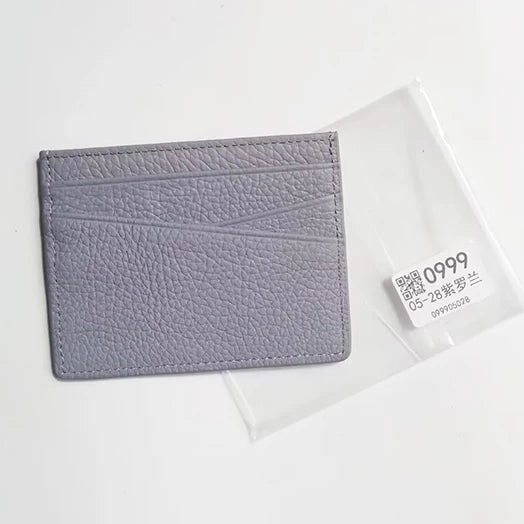 Porte-cartes en cuir véritable gris avec texture, montré dans une gaine en plastique transparent.