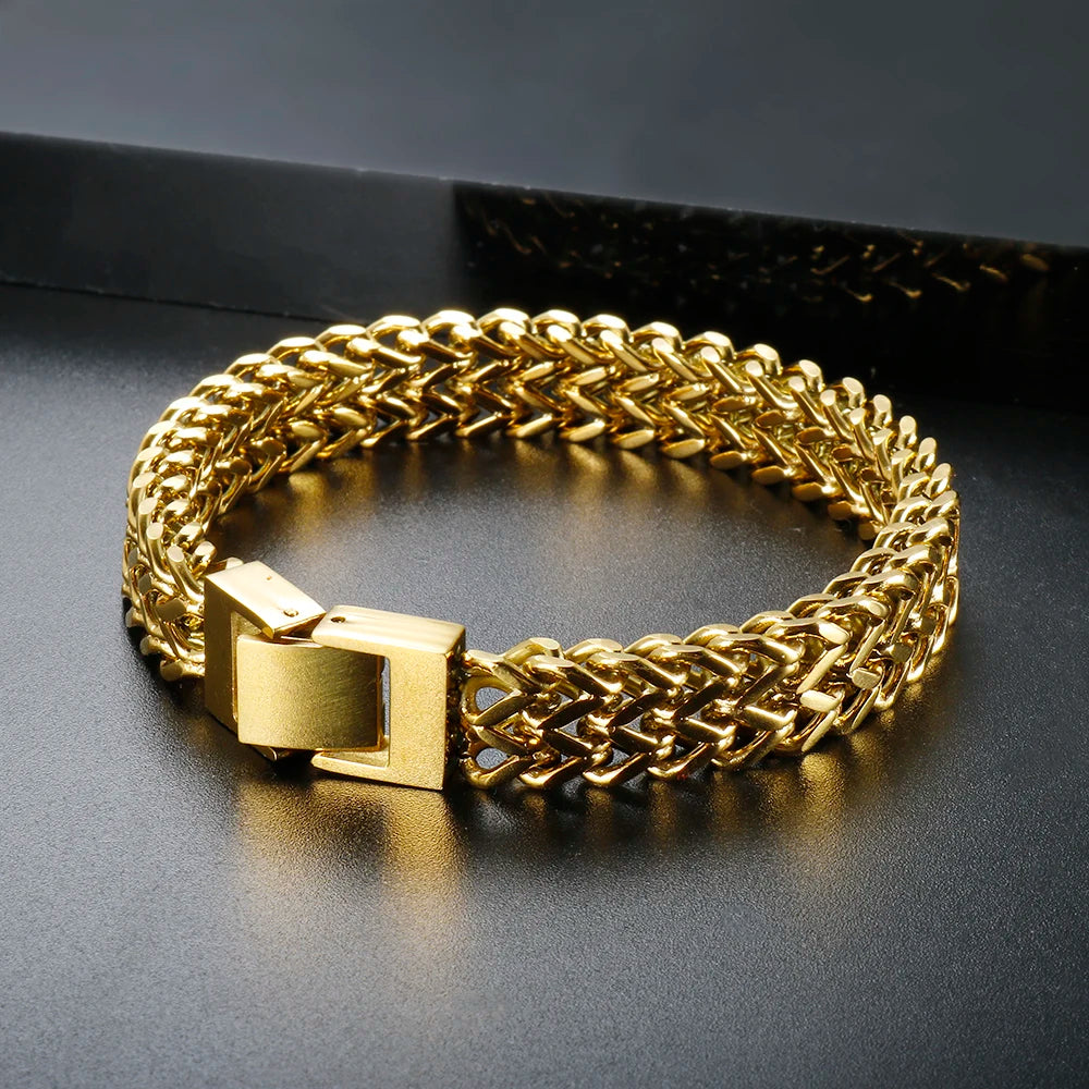 A chunky gold link chain bracelet worn on a dark surface.