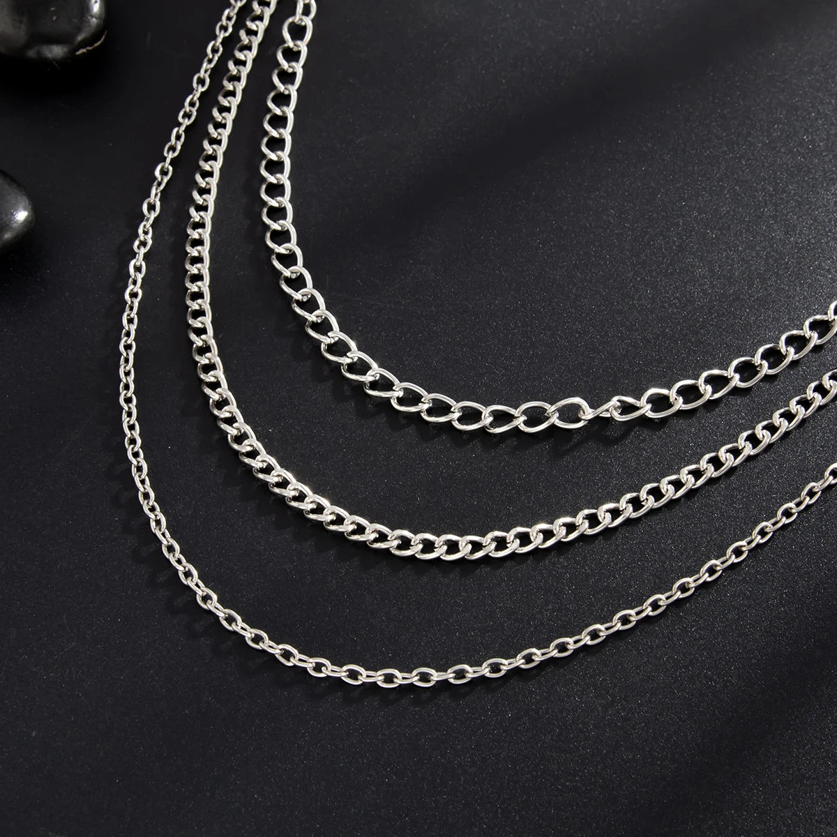 Silver punk star chain belt with pearl accents displayed against a dark background.