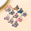 A set of colorful butterfly enamel charms jewelry featuring various shades of blue, green, and pink on a light background.
