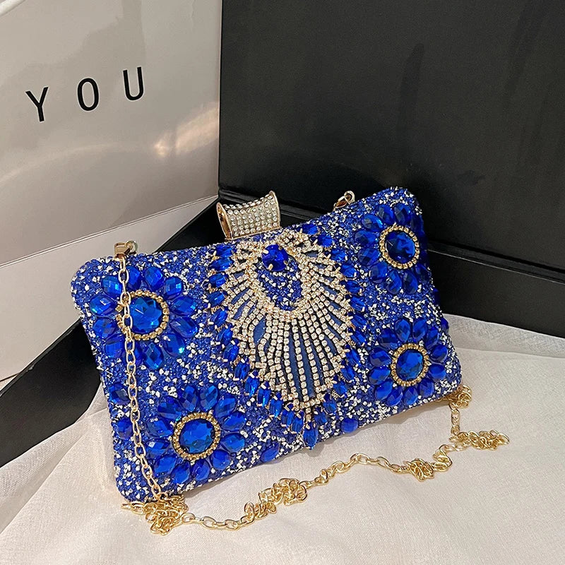 A royal blue rhinestone evening clutch bag with gold accents displayed on a white surface.
