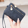 Una mano sostiene una cartera de cuero PU azul oscuro plegable con cremallera retro y herrajes dorados.