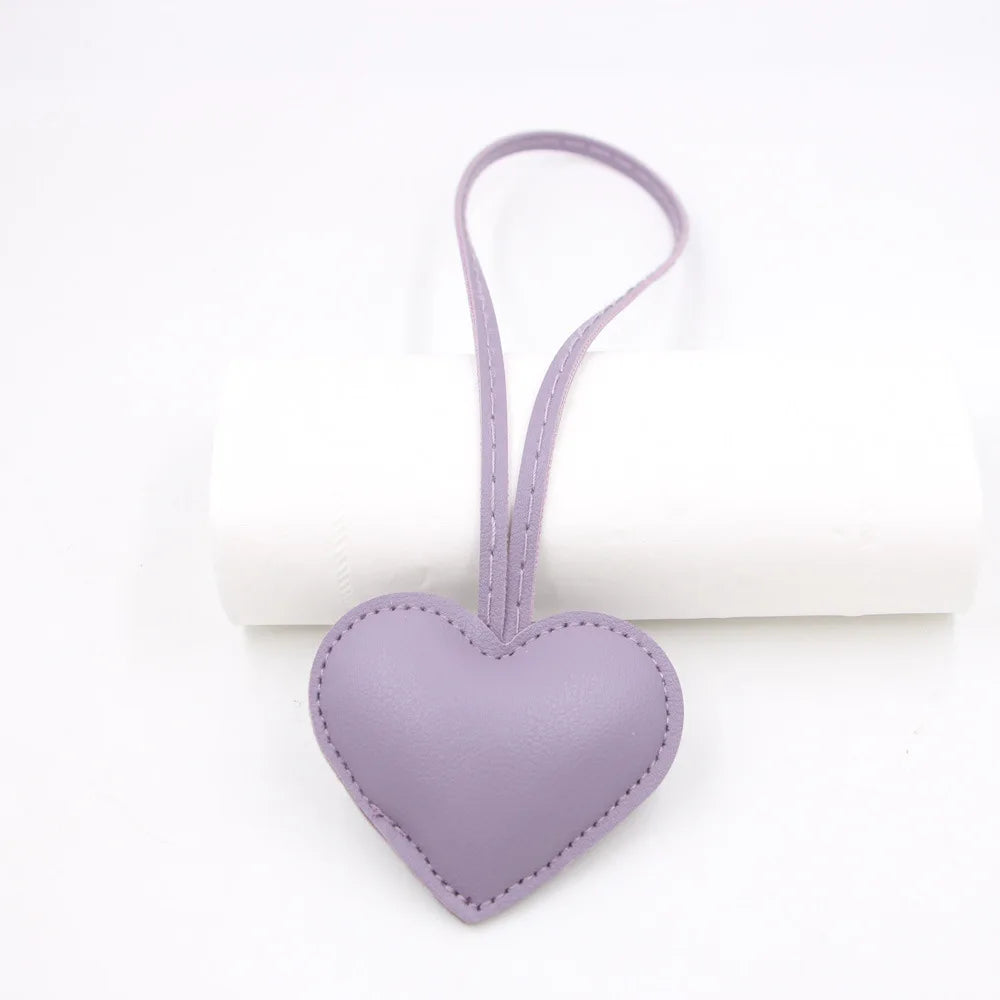 A small lavender PU leather heart shaped keychain with a loop for attachment.