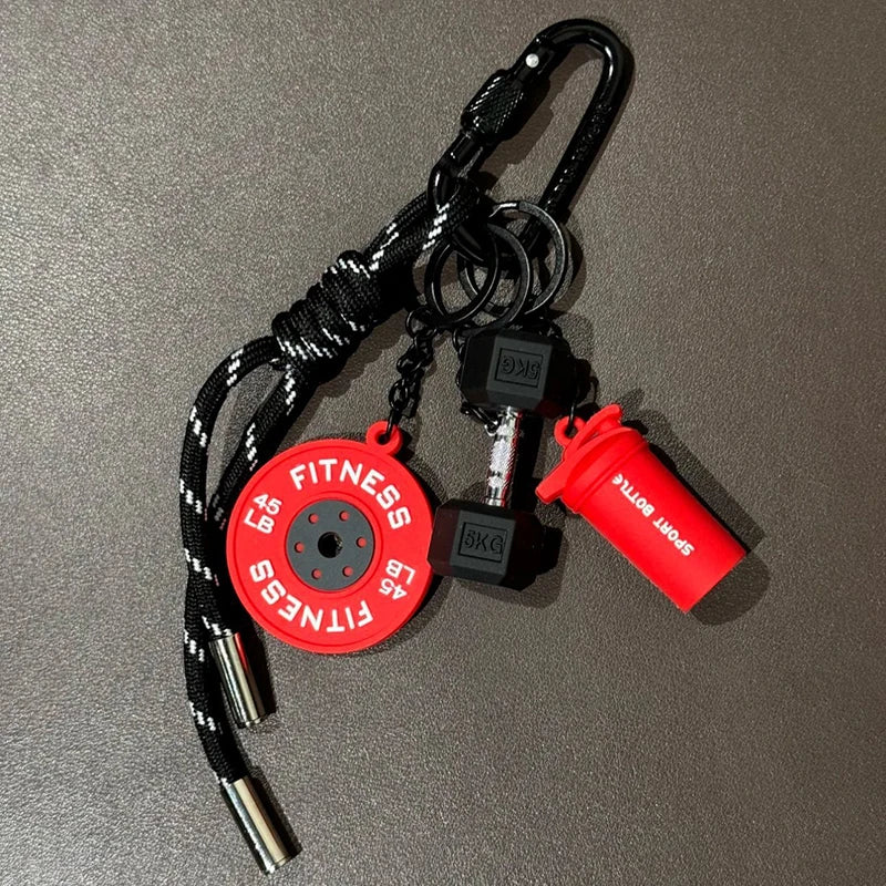 A black nylon fitness keychain featuring a red disc and an orange bottle attachment.