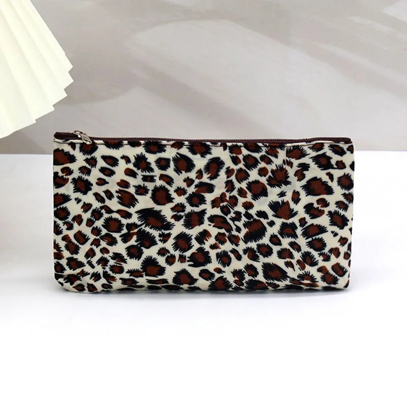 A brown and beige leopard print zippered cosmetic bag lying on a white surface.