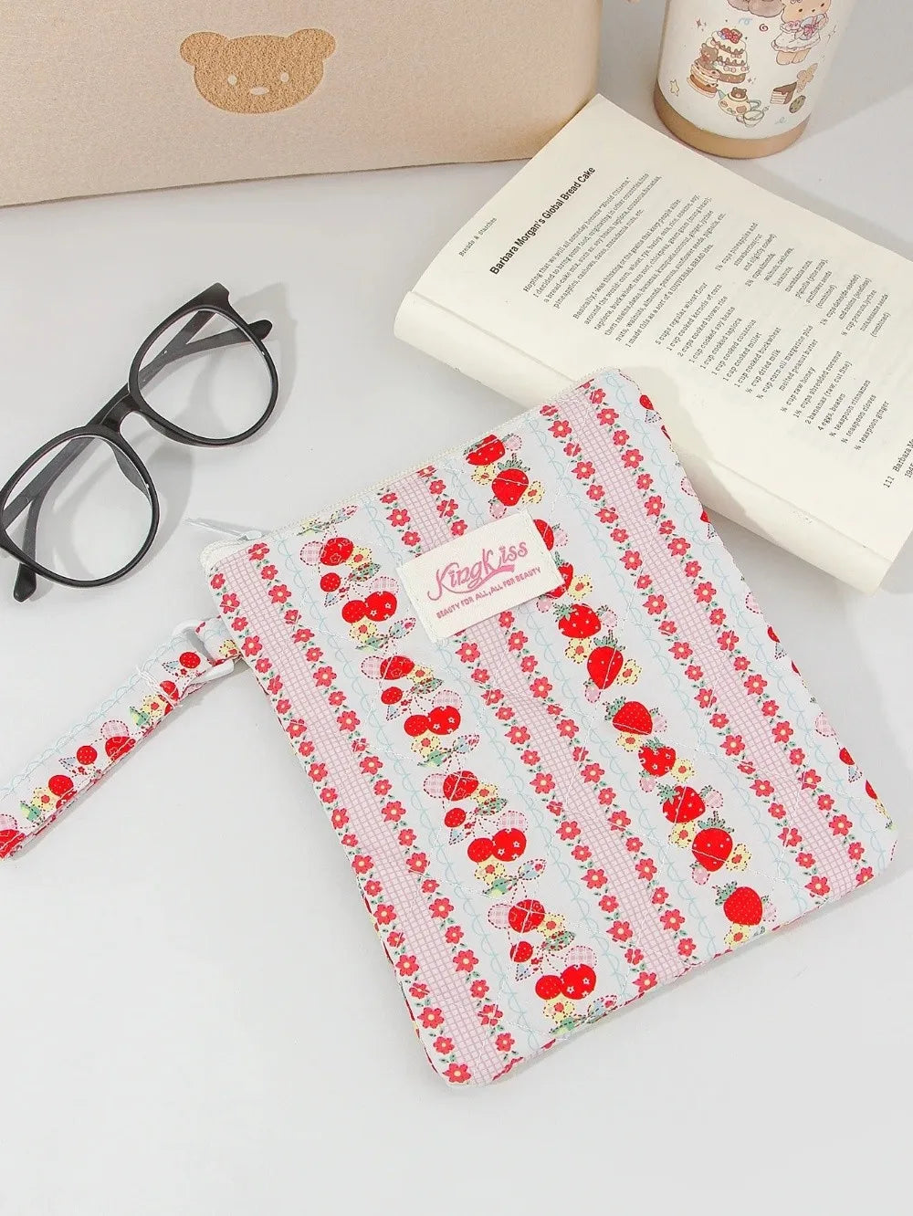 A pink and red floral plaid cotton tablet pouch with a secure closure resting on a white surface.